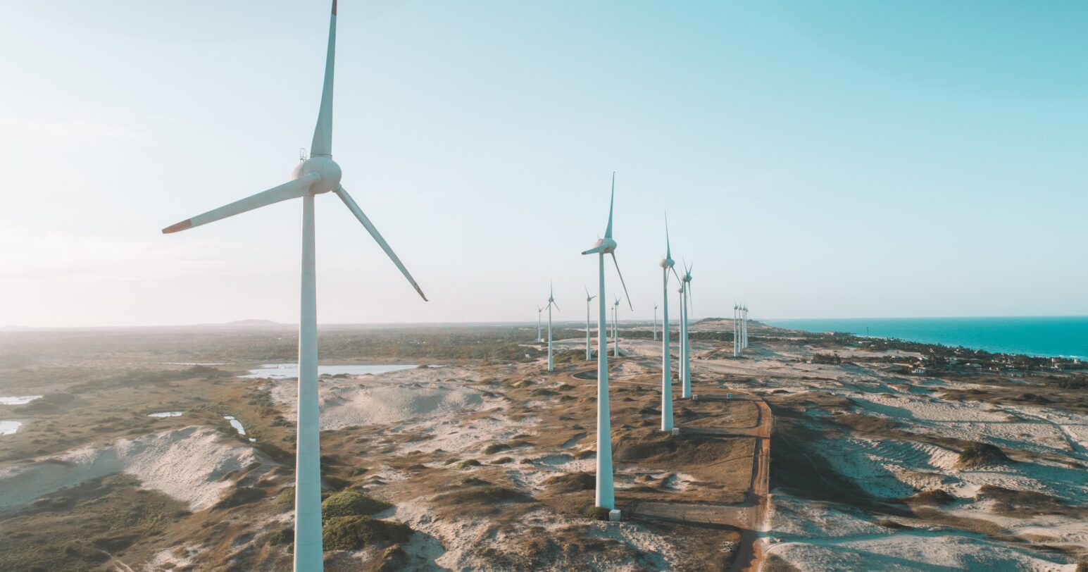 View of wind turbines along a beach.